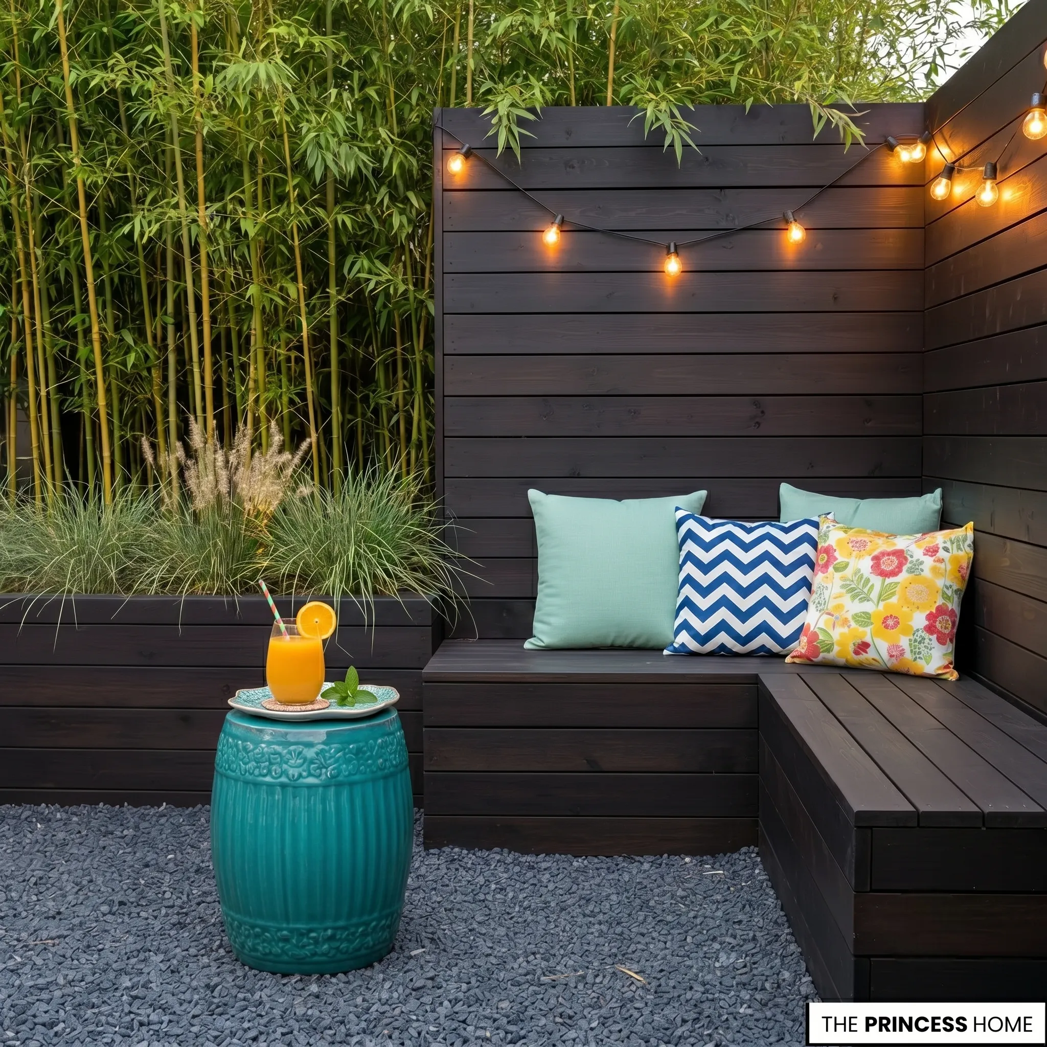 Dark wood corner bench with colorful cushions, string lights, teal ceramic side table, and a green bamboo backdrop.