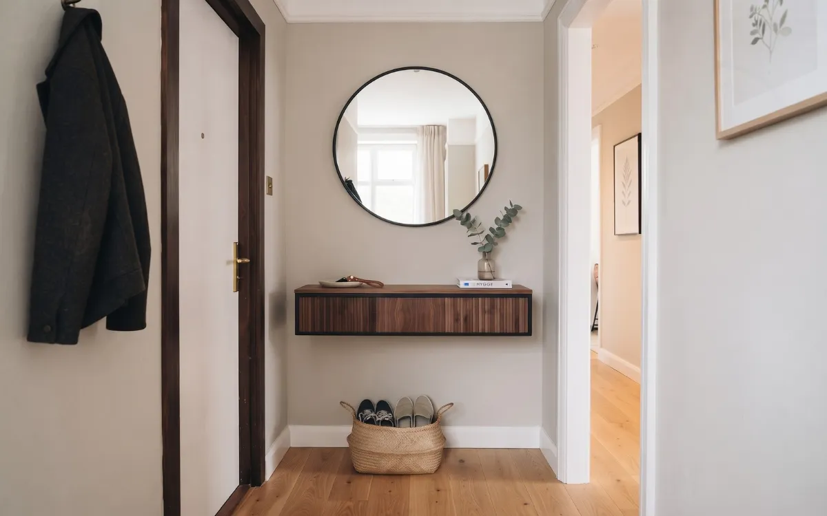 A compact contemporary entryway with a slim console, wall mirror, restrained accessories, and a clear walking path.